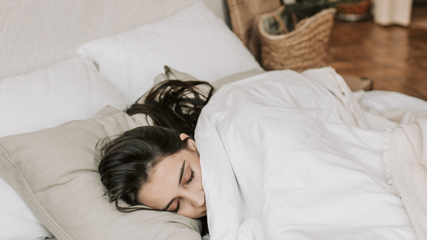 Sugar Island CBD melatonin image brunette girl sleeping in bed with all white bedding